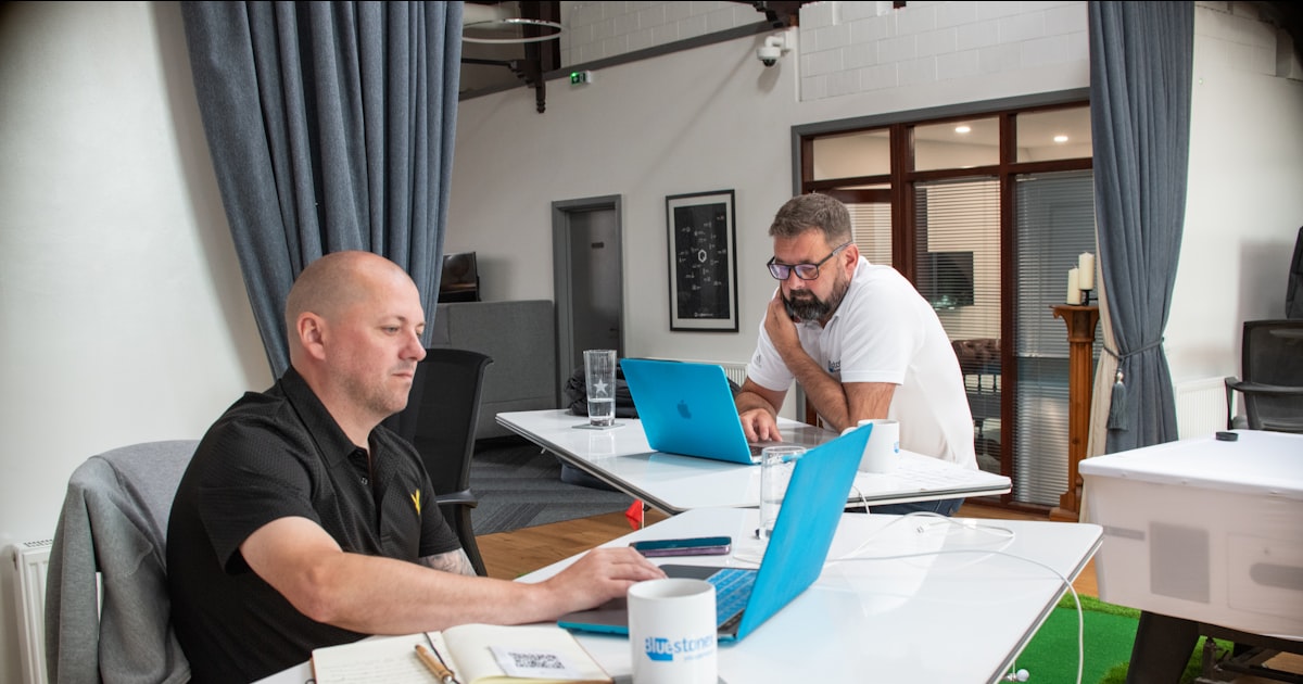 Two men working on laptops in a modern office.