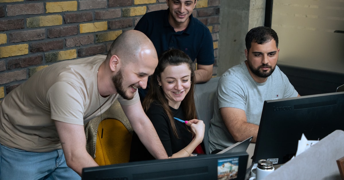 A group of people sitting around a laptop computer