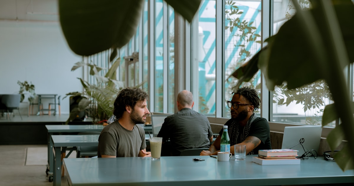 two men sitting at a table with a laptop