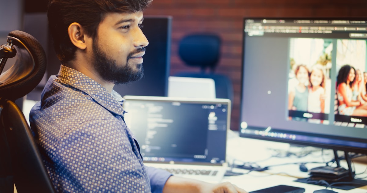 A man works at a computer, smiling.
