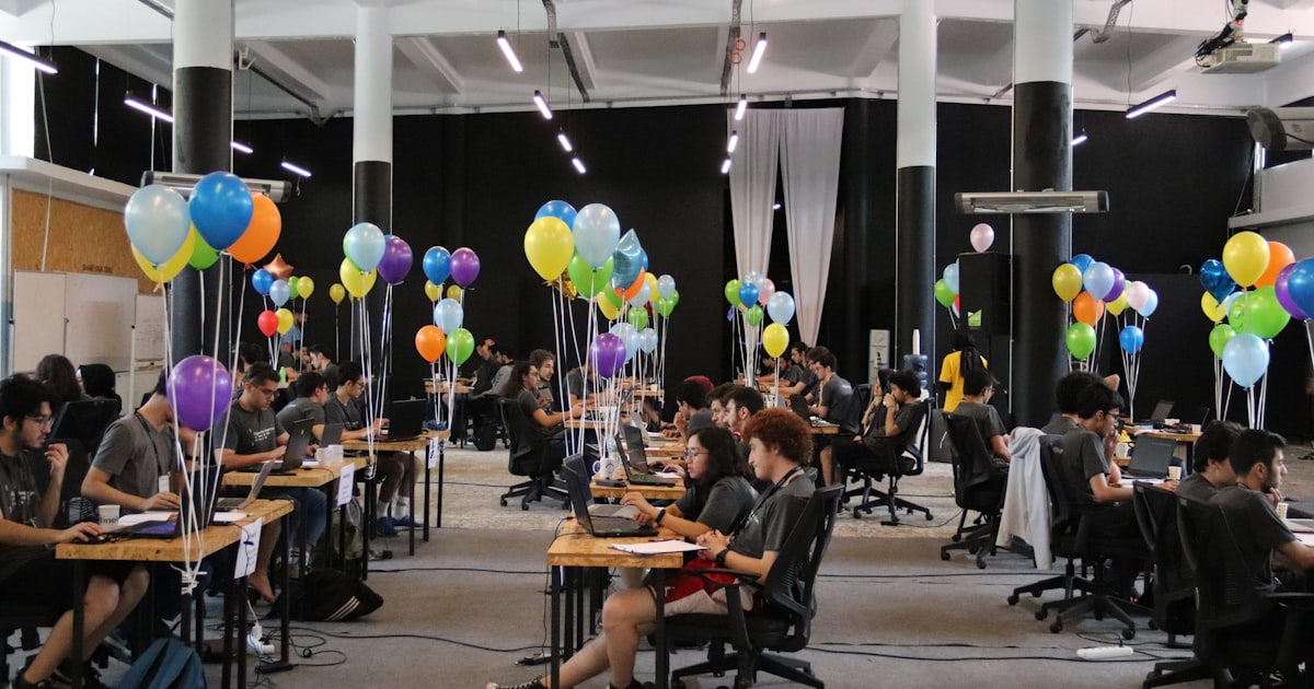 a group of people sitting at desks with balloons