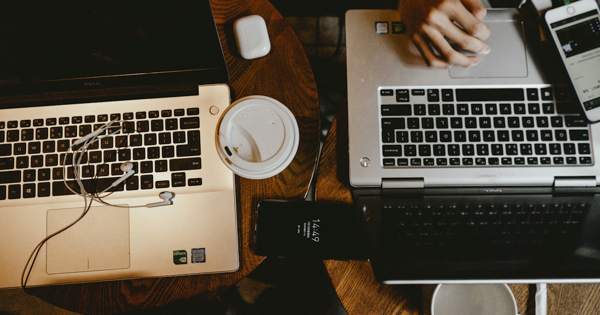 person using macbook pro on brown wooden table