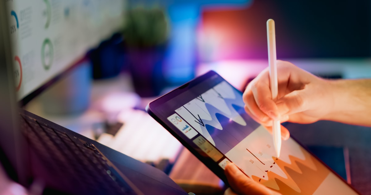 Person using stylus on tablet with charts.