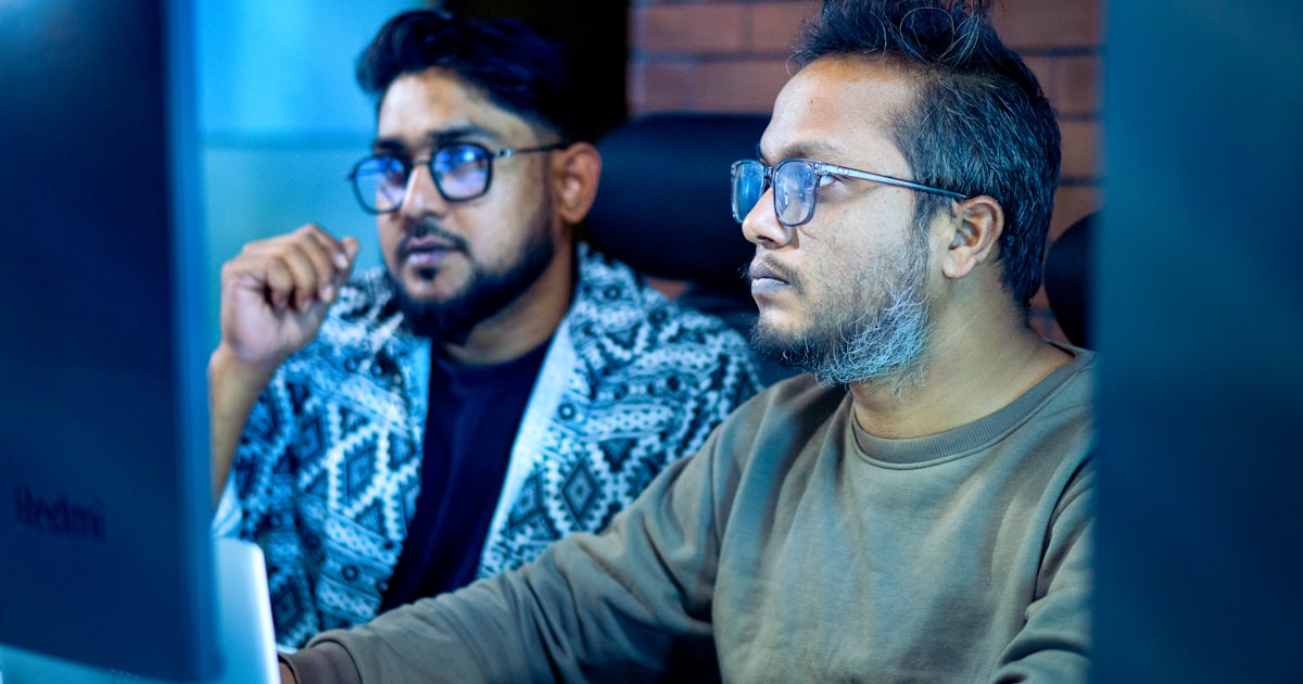 Two men looking intently at a computer screen.