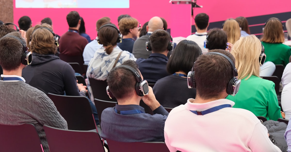 A group of people sitting in front of a pink wall