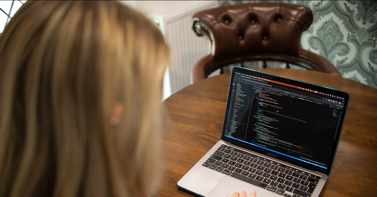 Woman typing code on a laptop computer.